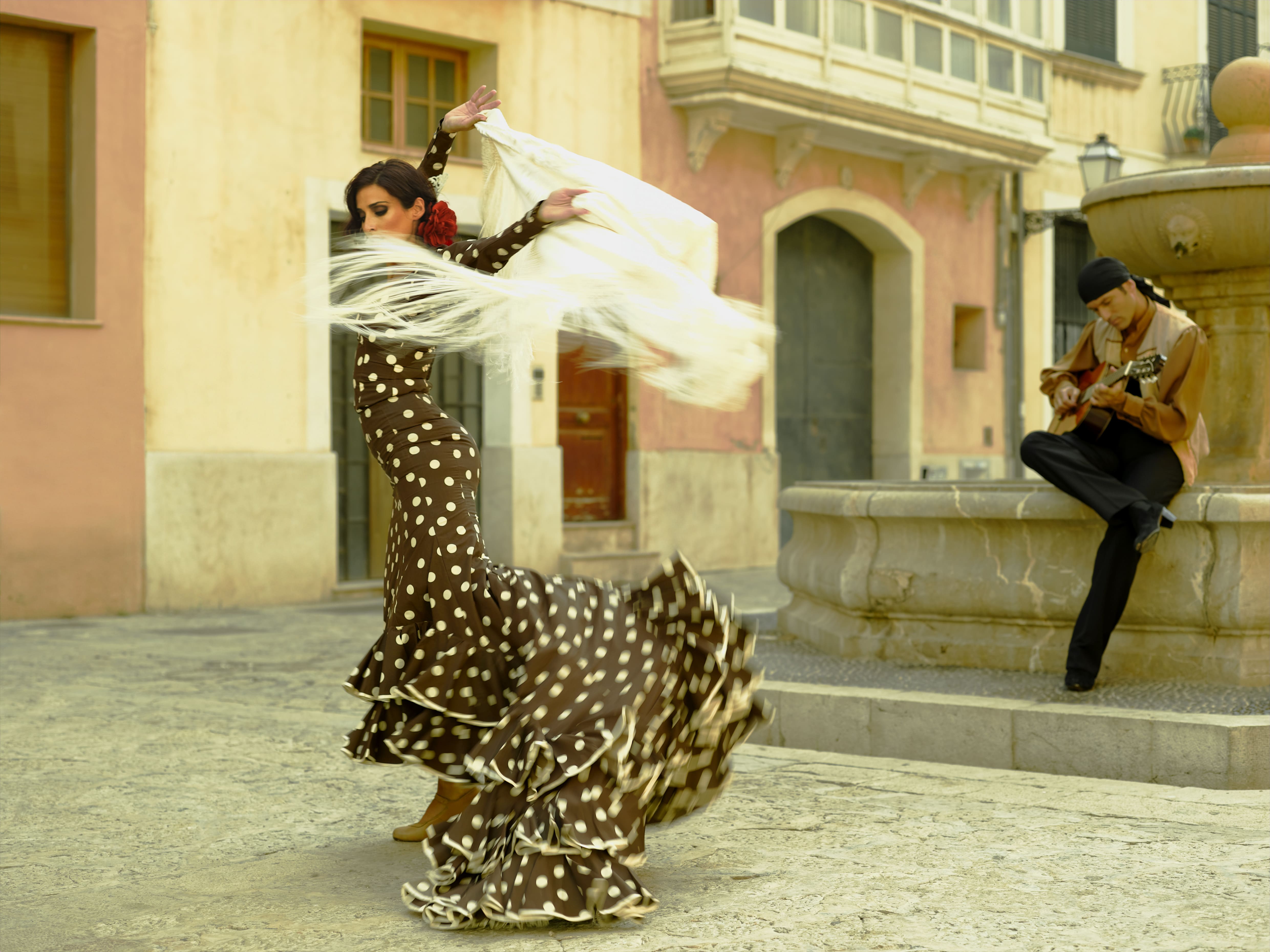 Bailarina flamenca vestida de rojo bailando en tablao andaluz, movimiento y pasión del baile flamenco tradicional